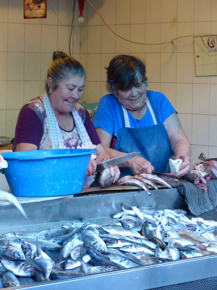 Ladies on a fish stall laughing gutting fish