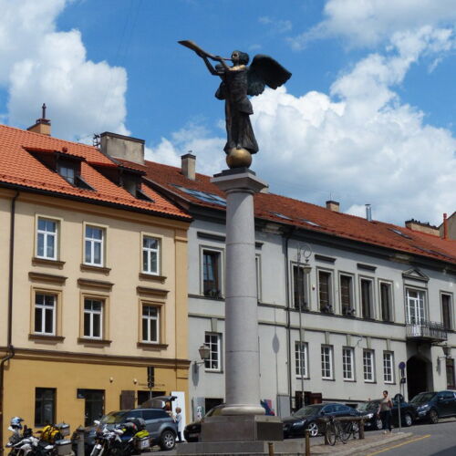 The Angel of Vilnius A street with a tall column on top of which stands an angel figure.